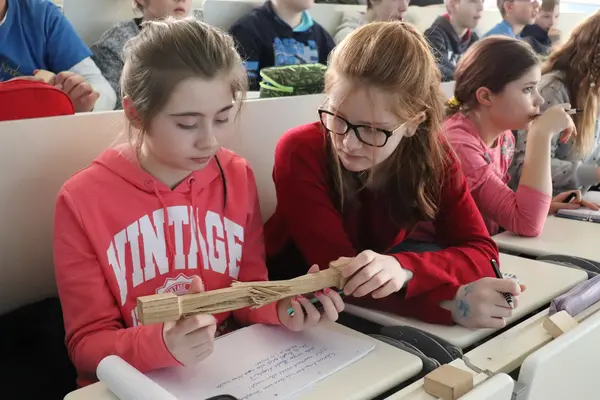 KinderUni Barnim Uckermark 2019 Zwei Mädchen besehen sich einen Prüfkörper. Dieser ist durch die wechselseitige Drehung in der Mitte aufgespalten.