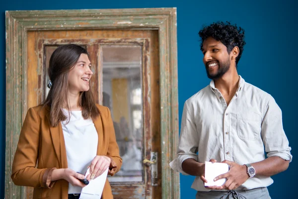 Starting a business during your studies Eine Studentin und ein Student stehen vorne und reden.