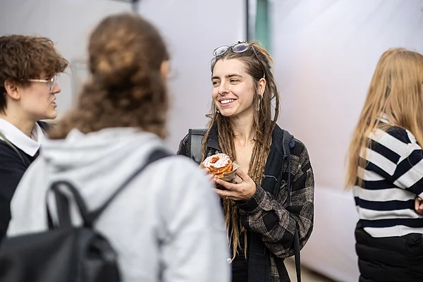 Eine Studentin hält einen Spritzkuchen in der Hand.