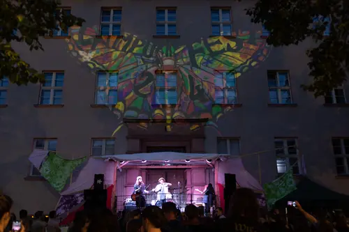 Ein Schmetterlingslogo wird mittels Beamer an die Hauswand projiziert.