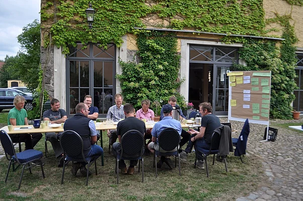 Teilnehmer der Cropping School diskutieren an einem Tisch Problemstellungen im Ackerbau und erarbeiten gemeinsam Lösungsmöglichkeiten.