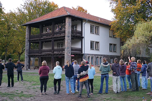 Menschen schauen zu einem Balkon, wo eine Person winkt