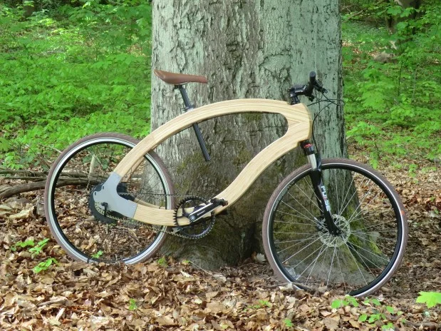Wood-E-Bike An einen dicken Buchenstamm ist ein Mountain-Bike gelehnt. Der Rahmen des Rades ist aus Holz. Dessen Form erinnert ein wenig an einen liegenden Tropfen. Es handelt sich um das Wood-E-Bike, welches in Kooperation zwischen der HNEE und der aceteam GmbH Buckow im Rahmen eines Forschungsprojektes entwickelt.