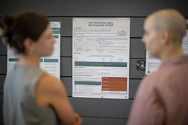Zwei Personen stehen vor einem wissenschaftlichen Poster und diskutieren.