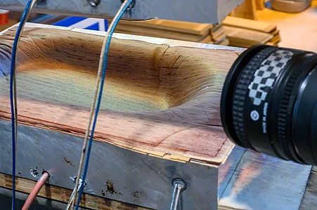 Ein Stück Holz wird geformt, während Messungen vorgenommen werden.