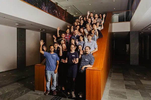Gute Stimmung Eine Gruppe Menschen steht auf einer Treppe für ein Gruppenfoto und winkt in die Kamera.