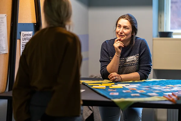 ein Frau steht hinter einem Tisch und berät eine Person