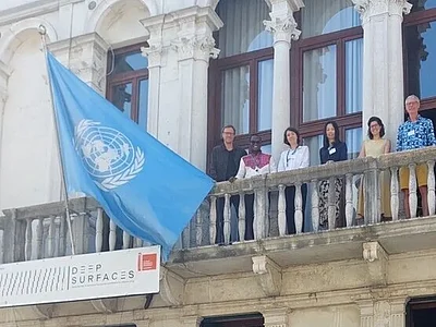 Menschen auf einem Balkon mit der UNESCO Flagge