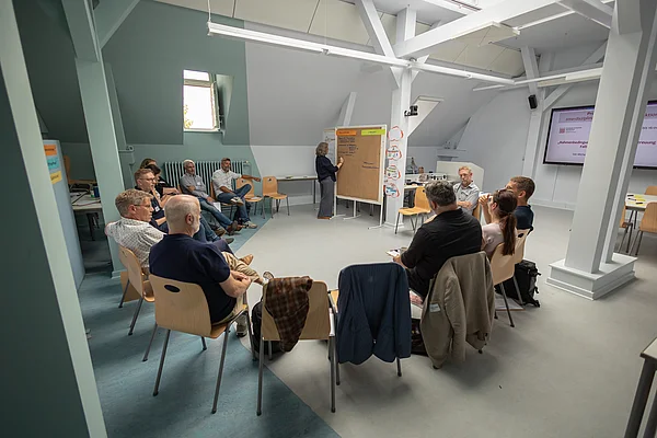 Menschen sitzen im Stuhlkreis