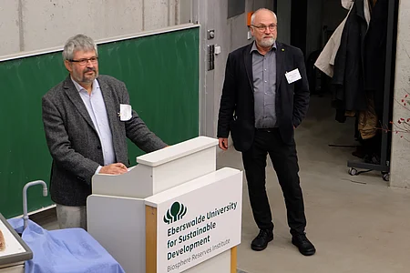  Two men are standing on a podium. 